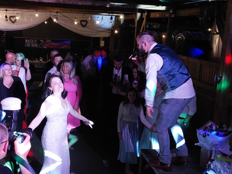 with DjitalMixX A crowded celebration with guests dancing and a man performing on a table.